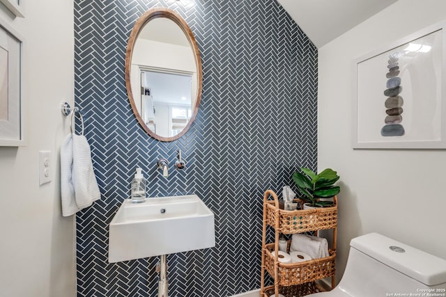 half bath featuring tile walls, toilet, and a sink