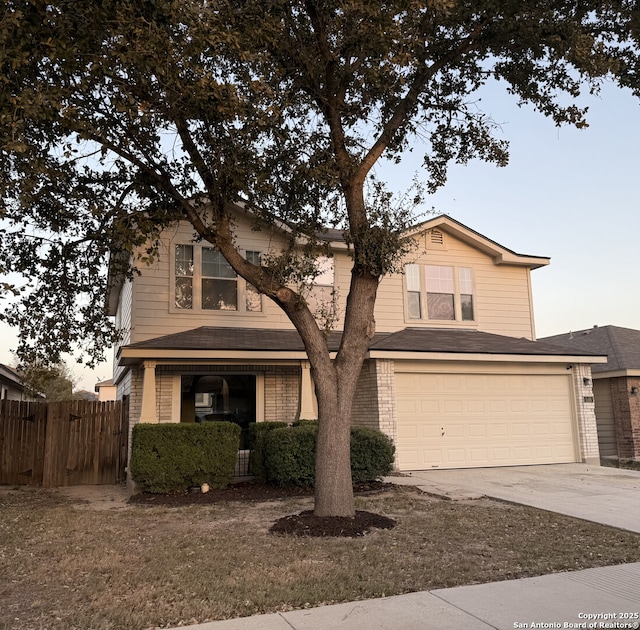 traditional home featuring brick siding, driveway, an attached garage, and fence