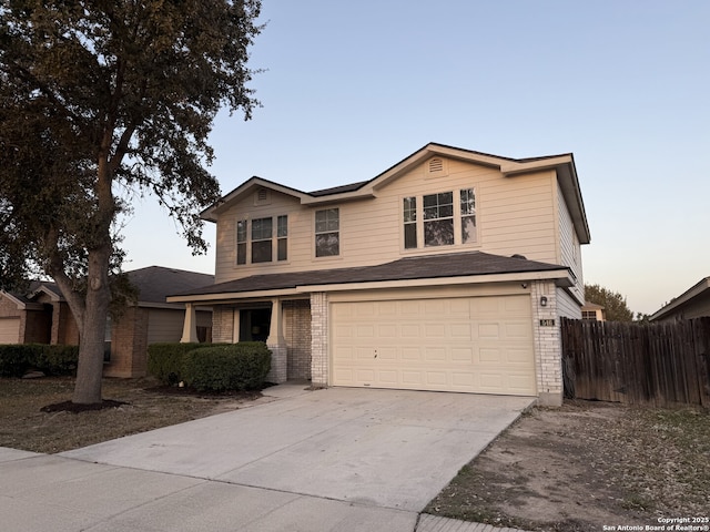 traditional-style home featuring brick siding, an attached garage, driveway, and fence