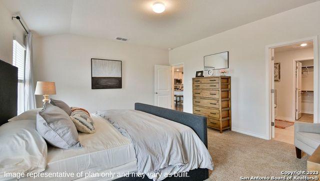 bedroom with lofted ceiling, baseboards, visible vents, and light carpet