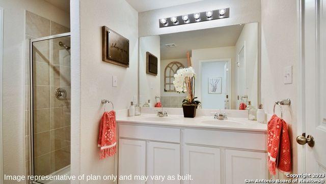 bathroom featuring a sink, double vanity, and a shower stall