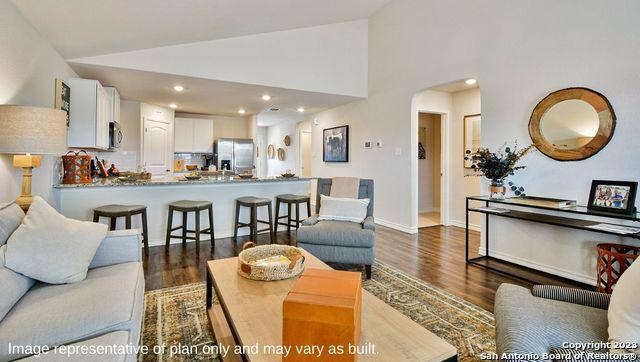 living area with recessed lighting, baseboards, arched walkways, and dark wood-type flooring