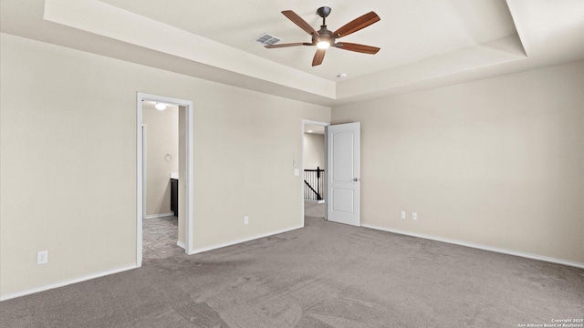 unfurnished bedroom with visible vents, a raised ceiling, carpet, and baseboards