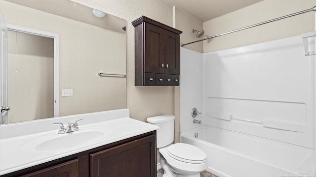 bathroom with vanity, toilet, washtub / shower combination, and a textured wall