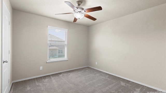 carpeted spare room with baseboards and a ceiling fan