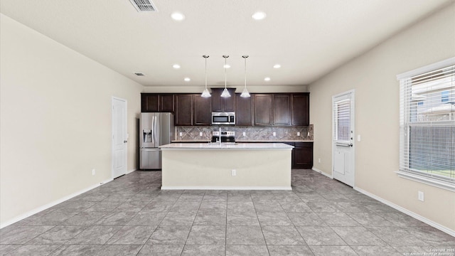 kitchen featuring visible vents, backsplash, dark brown cabinets, an island with sink, and appliances with stainless steel finishes