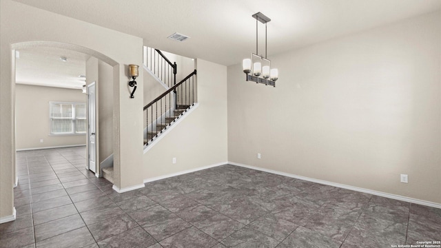 unfurnished room with visible vents, dark tile patterned floors, arched walkways, baseboards, and stairs