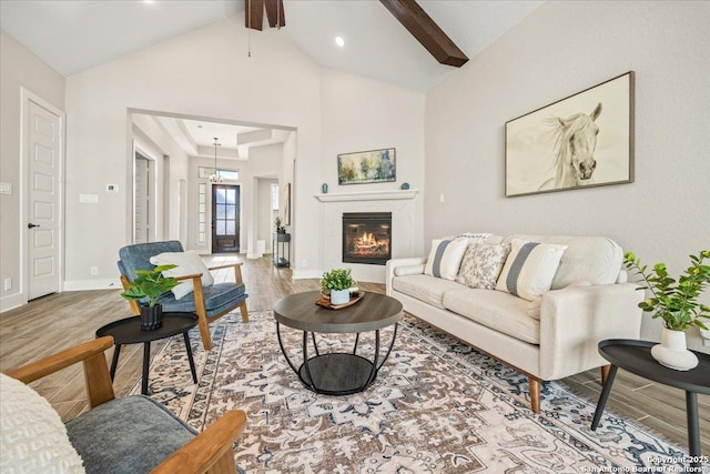 living area with a ceiling fan, wood finished floors, baseboards, beam ceiling, and a tile fireplace