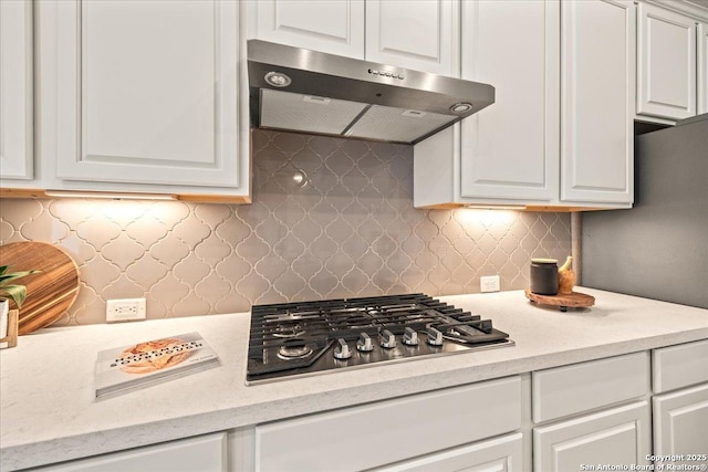 kitchen featuring tasteful backsplash, white cabinetry, extractor fan, and stainless steel gas stovetop