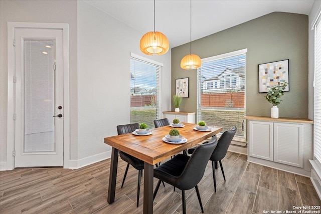 dining room featuring vaulted ceiling, wood finished floors, and baseboards