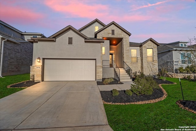 view of front of house with driveway, stucco siding, a garage, stone siding, and a lawn