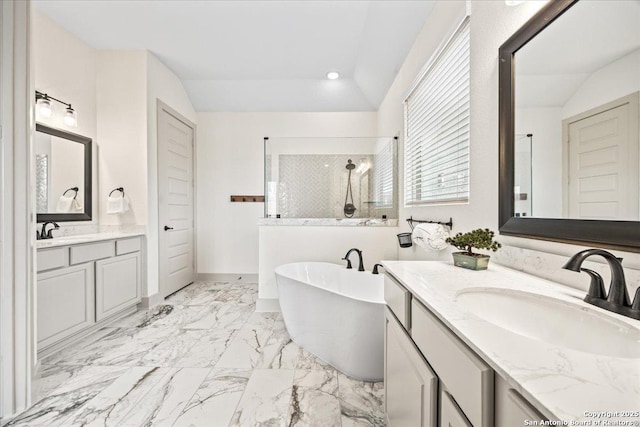 bathroom featuring a freestanding bath, vaulted ceiling, tiled shower, and a sink