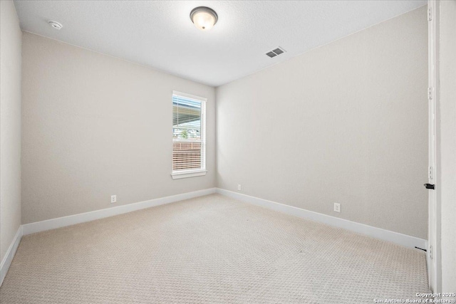 empty room featuring a textured ceiling, baseboards, visible vents, and light carpet