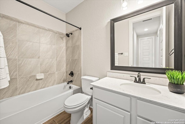 full bath with vanity, wood finished floors, shower / bathing tub combination, toilet, and a textured wall