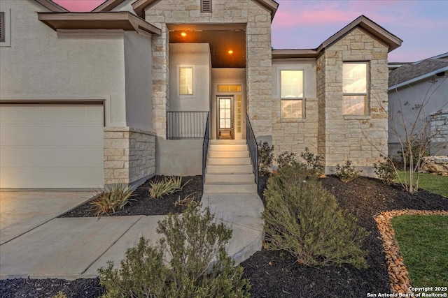 view of front facade with an attached garage, stone siding, and stucco siding