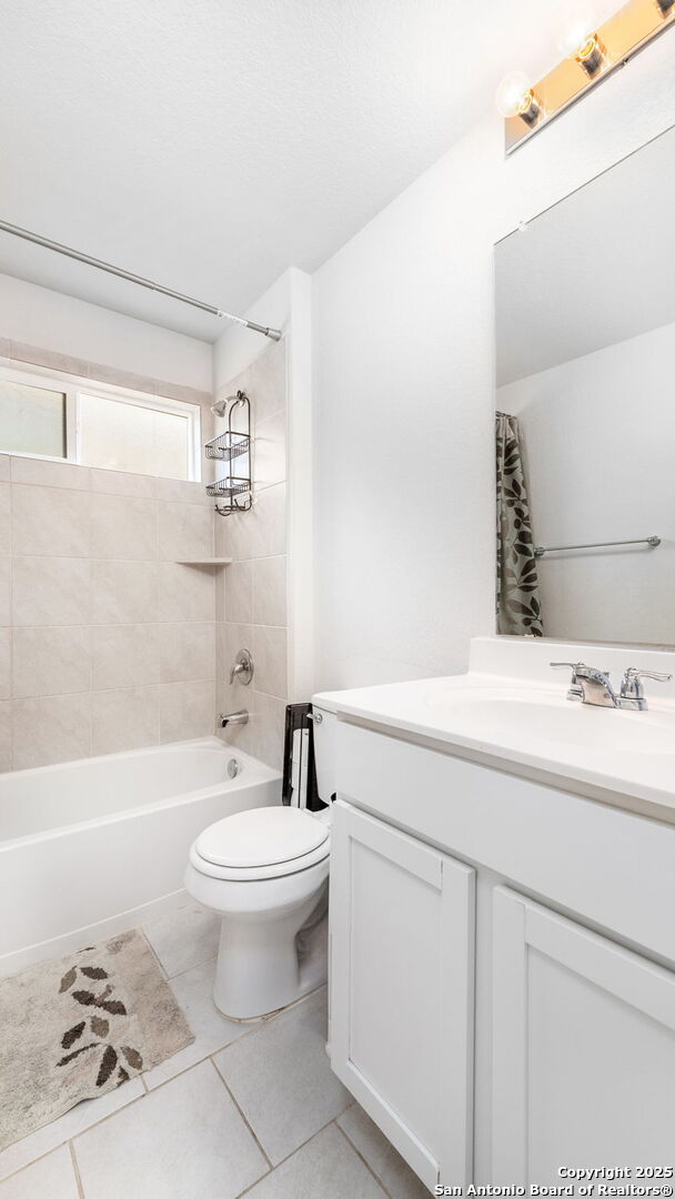 bathroom featuring tile patterned floors, toilet, vanity, and shower / bathtub combination with curtain