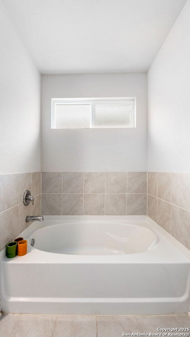 full bath featuring a wealth of natural light, a garden tub, and tile patterned floors