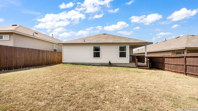 back of house featuring a lawn and a fenced backyard