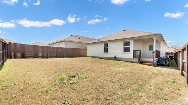 back of property with a fenced backyard and a yard