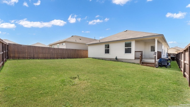 rear view of property featuring a lawn and a fenced backyard