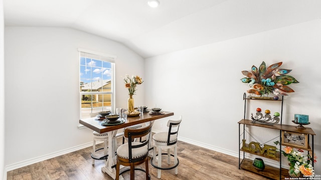 dining area with baseboards, lofted ceiling, and wood finished floors