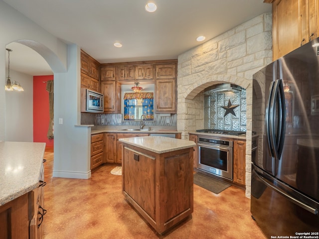 kitchen with a sink, backsplash, a center island, stainless steel appliances, and arched walkways