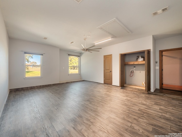 unfurnished bedroom with attic access, wood finished floors, visible vents, and baseboards