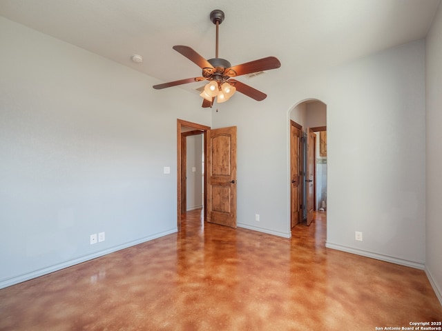 empty room with baseboards, arched walkways, and a ceiling fan