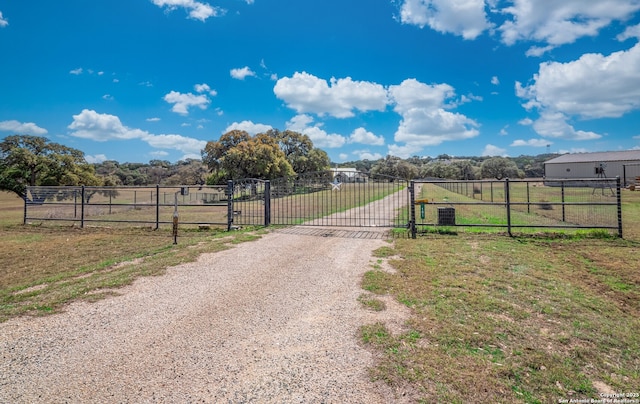 view of road featuring a gated entry, a rural view, gravel driveway, and a gate