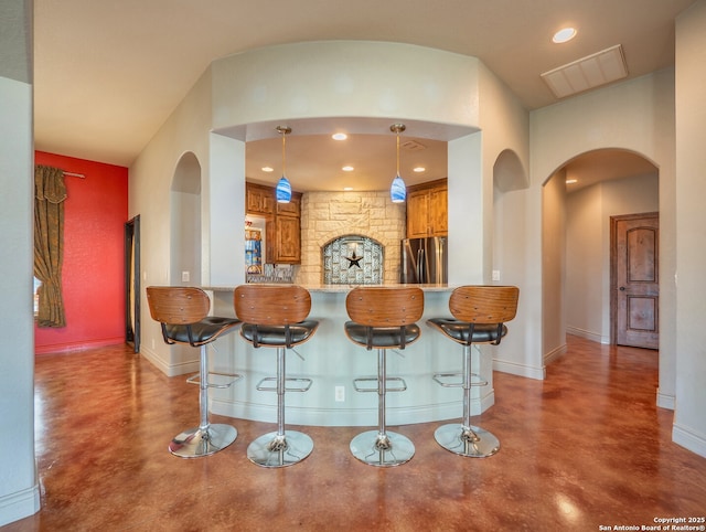 kitchen featuring arched walkways, visible vents, freestanding refrigerator, and finished concrete floors