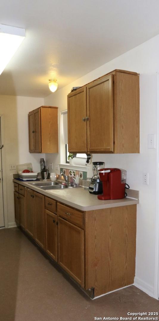 kitchen with brown cabinets, light countertops, baseboards, and a sink