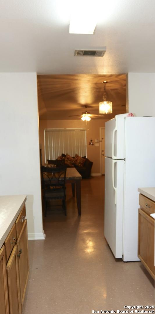 kitchen featuring visible vents, freestanding refrigerator, ceiling fan, light countertops, and brown cabinets