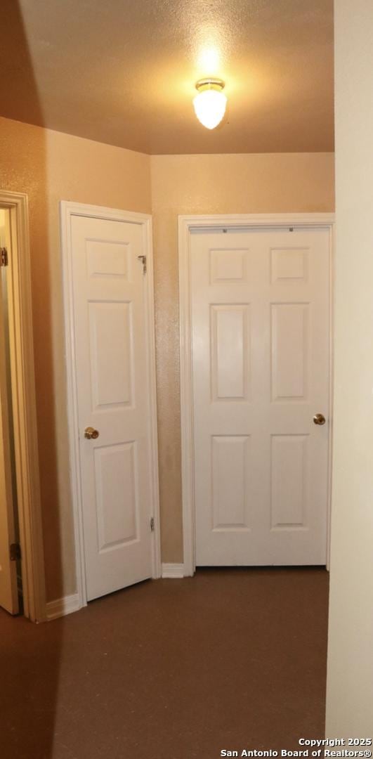 hallway with baseboards and a textured ceiling