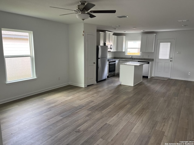 kitchen with visible vents, dark wood-type flooring, a ceiling fan, a kitchen island, and appliances with stainless steel finishes