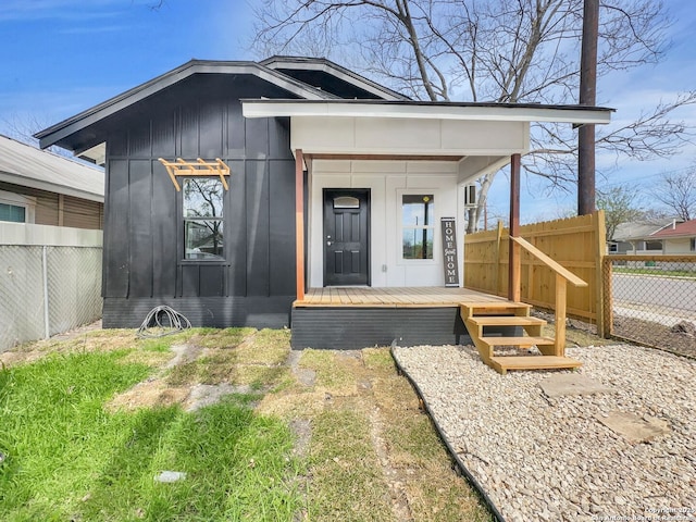 entrance to property featuring fence and board and batten siding