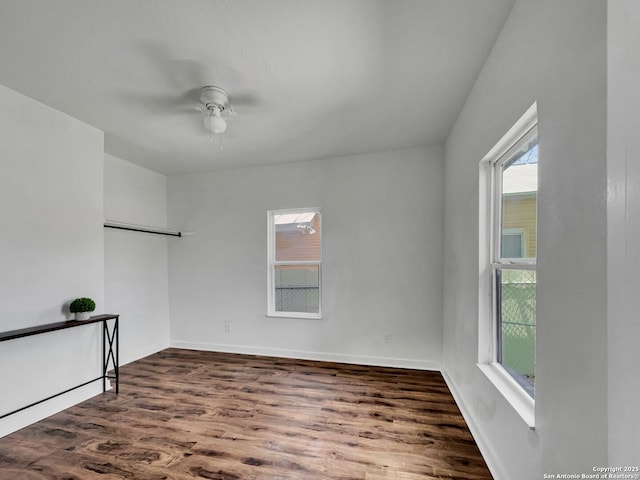 unfurnished room featuring a ceiling fan, plenty of natural light, wood finished floors, and baseboards