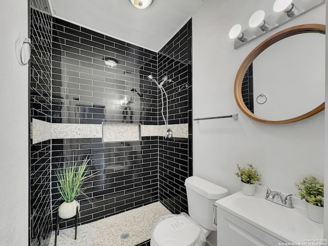 bathroom featuring tiled shower, toilet, and vanity