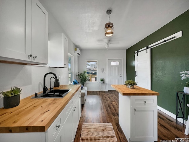 kitchen with dark wood-style floors, a sink, butcher block countertops, white cabinets, and a wall mounted air conditioner