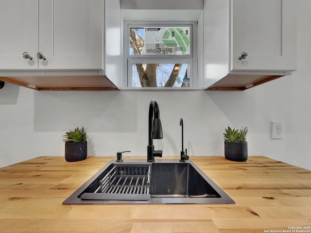 room details with white cabinets, wooden counters, and a sink