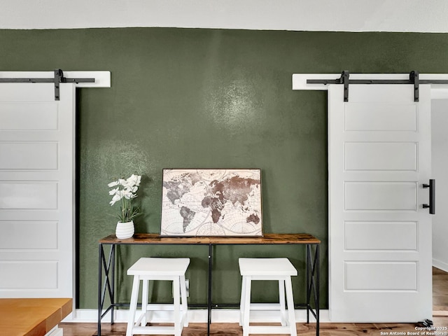 room details featuring baseboards, a barn door, and wood finished floors