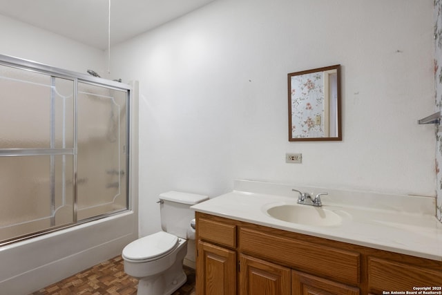 bathroom featuring enclosed tub / shower combo, toilet, and vanity