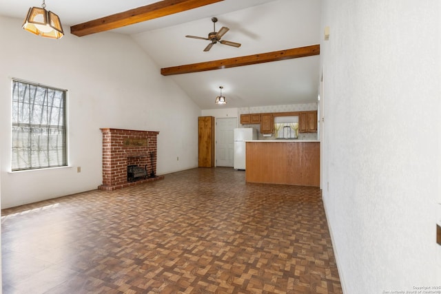 unfurnished living room featuring beamed ceiling, high vaulted ceiling, a healthy amount of sunlight, and a ceiling fan