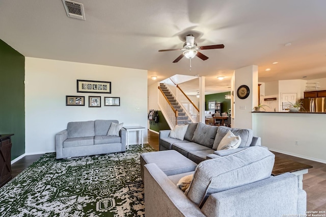 living area with visible vents, a ceiling fan, dark wood-style floors, baseboards, and stairs