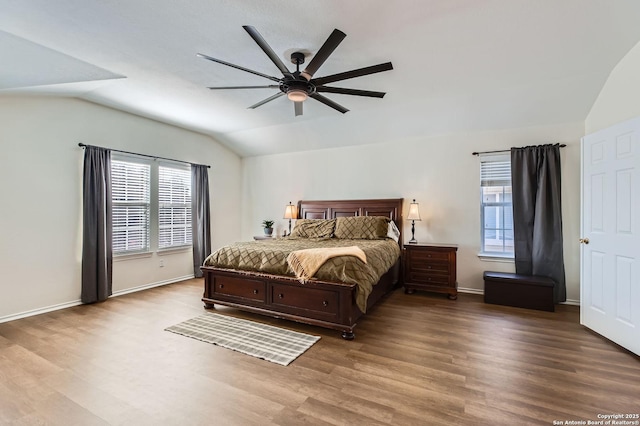 bedroom with multiple windows, baseboards, lofted ceiling, and wood finished floors