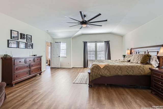 bedroom featuring a ceiling fan, vaulted ceiling, wood finished floors, and baseboards