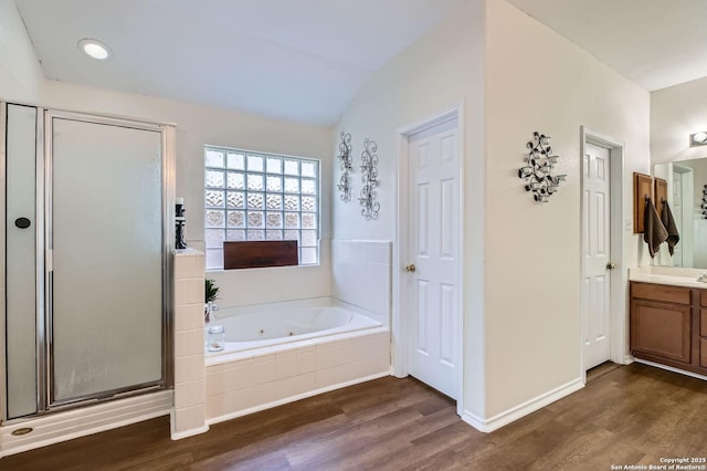 bathroom featuring vanity, a shower stall, a jetted tub, and wood finished floors