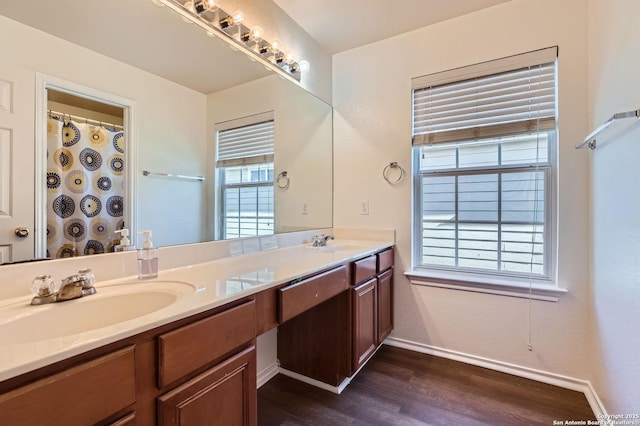 bathroom featuring double vanity, wood finished floors, baseboards, and a sink