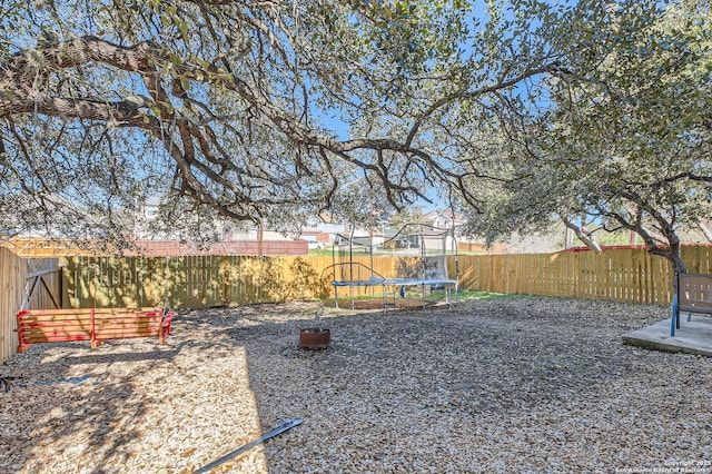 view of yard featuring a trampoline and a fenced backyard