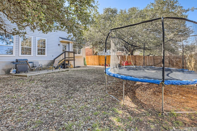 view of yard with a trampoline and fence