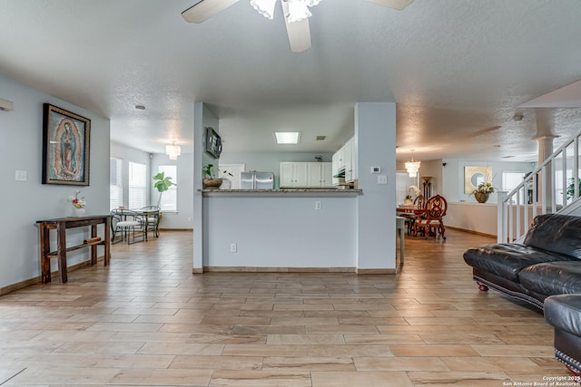 kitchen with light wood finished floors, open floor plan, freestanding refrigerator, white cabinetry, and a ceiling fan